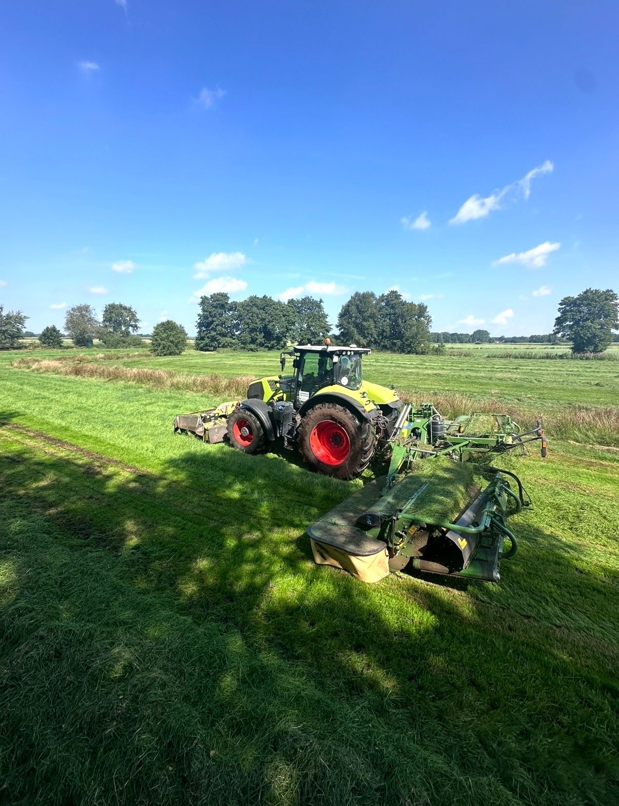 Schlepper mit Front- und Schmetterlings-Heckmähwerk beim Grasmähen