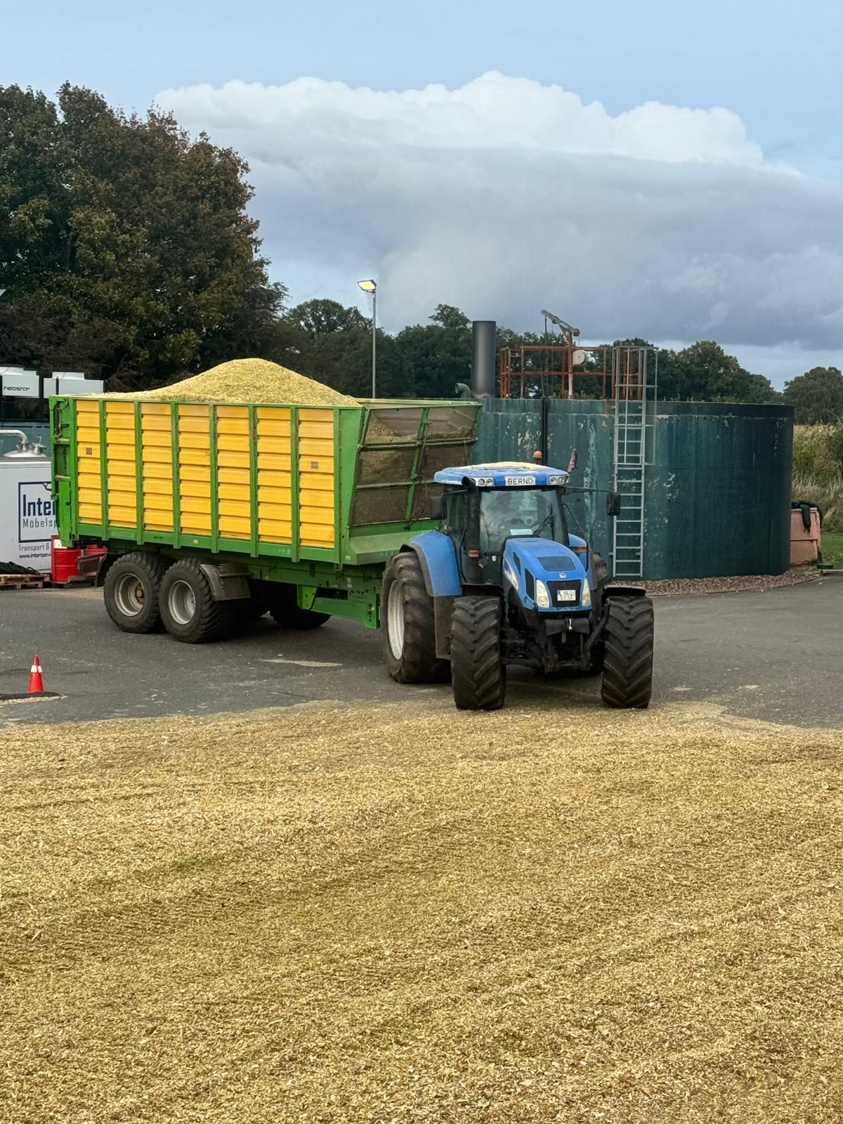 Schlepper mit Mais-Anhänger liefert Häckselgut an einer Biogas-Anlage an